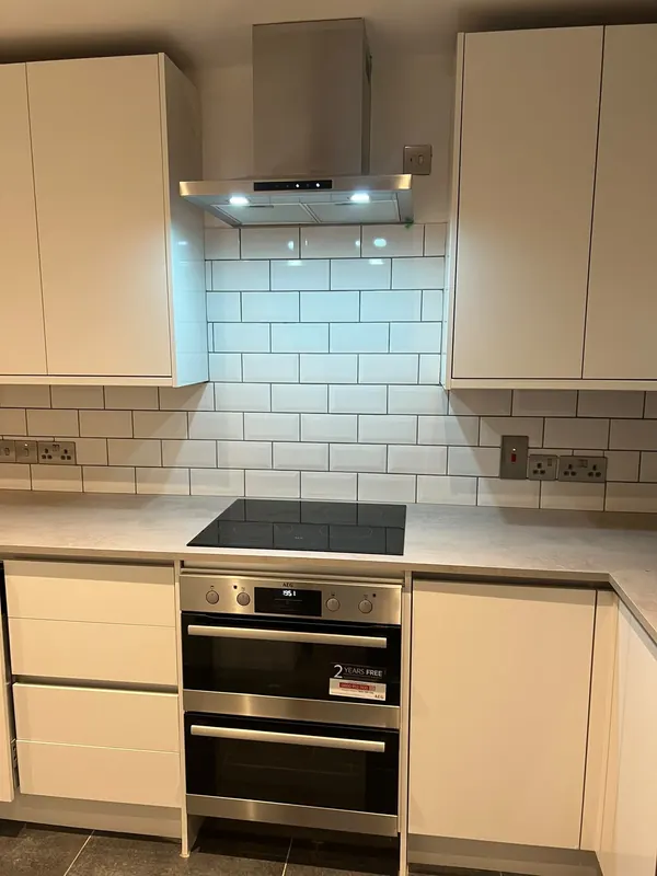 Kitchen with cream units, white metro tiles, a cooker hood and a built-in double oven