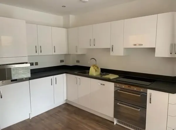 L-shaped kitchen with white gloss units and a black worktop