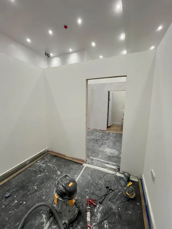 Room in a shop unit with new white walls, a doorway and ceiling spotlights